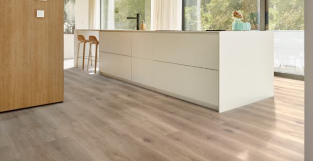 light wood look luxury vinyl plank flooring in kitchen with white cabinets and wood barstools.